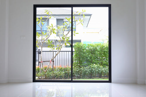 Modern sliding glass door with black frame leading to a garden view