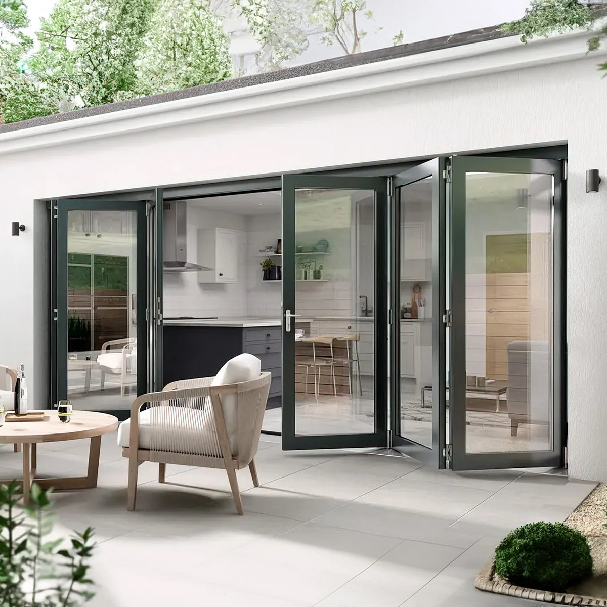 Modern patio with glass doors leading to a kitchen, featuring outdoor furniture and greenery.